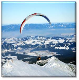Paraglider roaring above snow-capped peaks